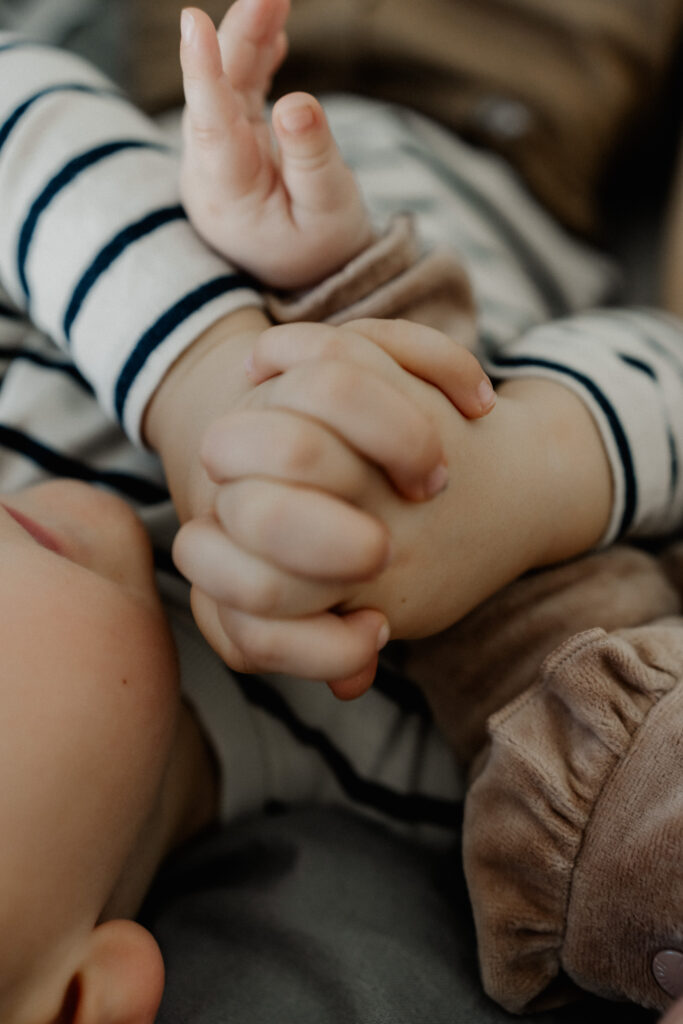 Familienshooting. Nahaufnahme Hände der Geschwister.