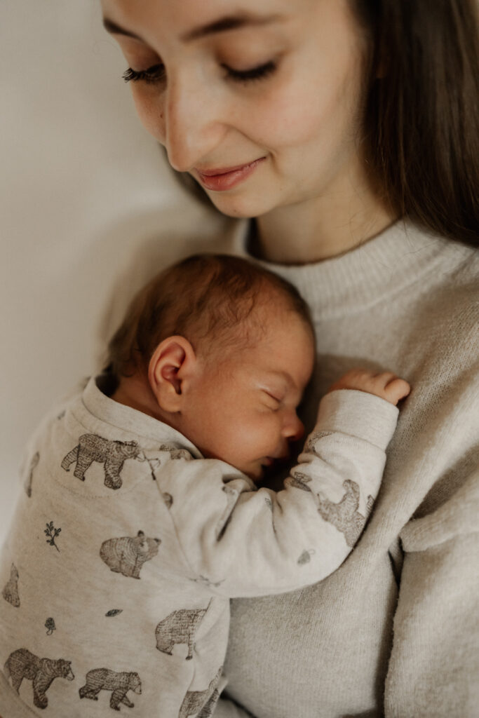 Newbornshooting Homestory. Neugeborenes schläft mit dem Kopf an Mamas Brust.