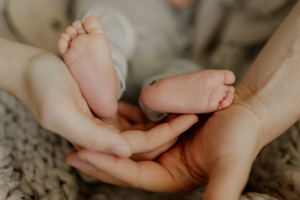 Newbornshooting Eppingen Homestory. Babyfüße werden von den Händen der Eltern gehalten.