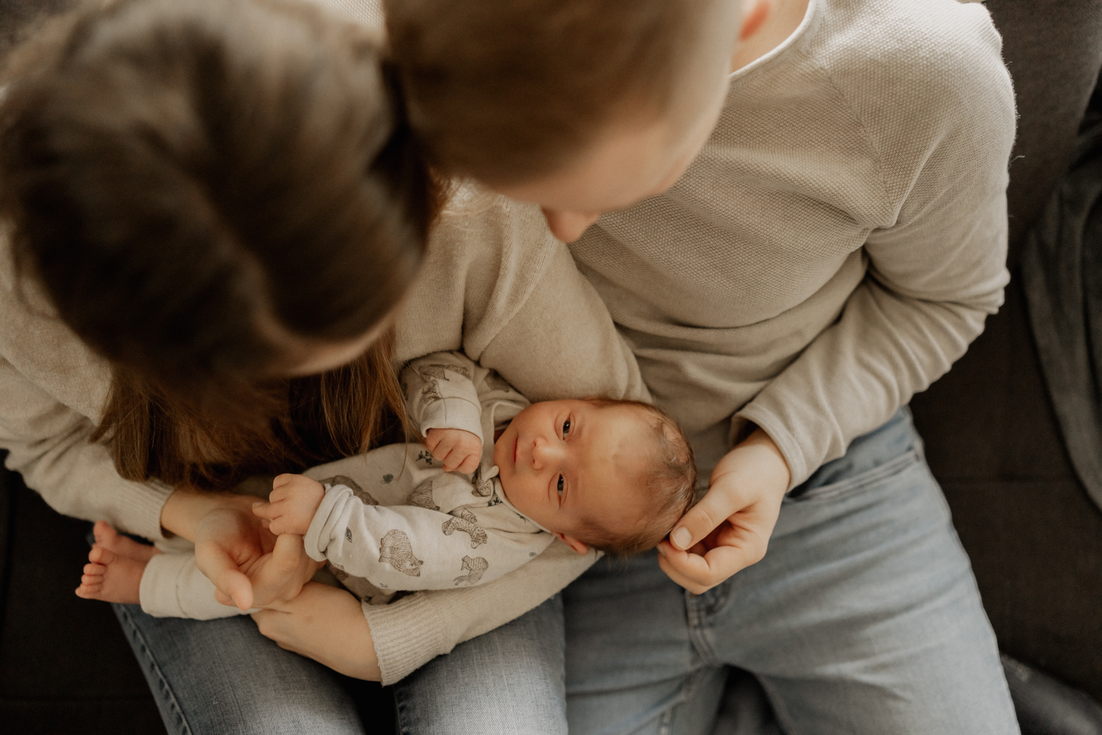 Newbornshooting Eppingen Homestory. Mama hält Baby auf dem Arm. Papa und Mama schauen das Neugeborene liebevoll an.