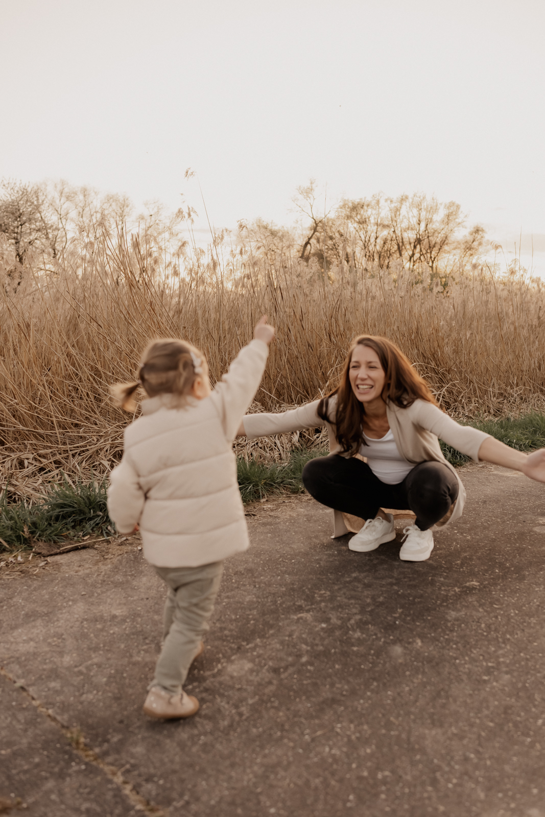 Babybauchshooting Eppingen. Große Schwester läuft in ausgebreitete Arme der Mama.